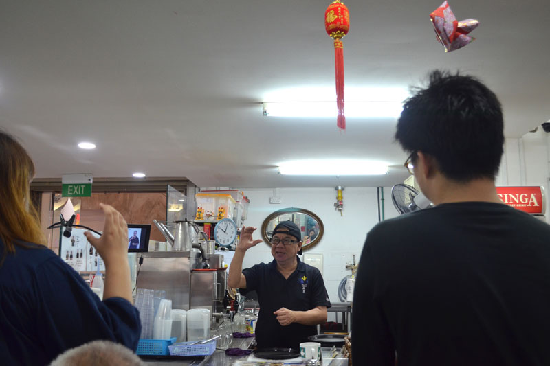 Drinks stall manager Peter Ong, who is hearing-impaired, teaching us to order drinks in sign language